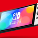 A Nintendo Switch OLED model hangs in front of a red background.
